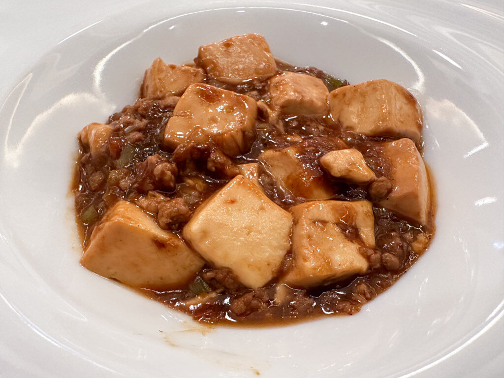 深さのある白いお皿の中央に麻婆豆腐が盛り付けられている。
